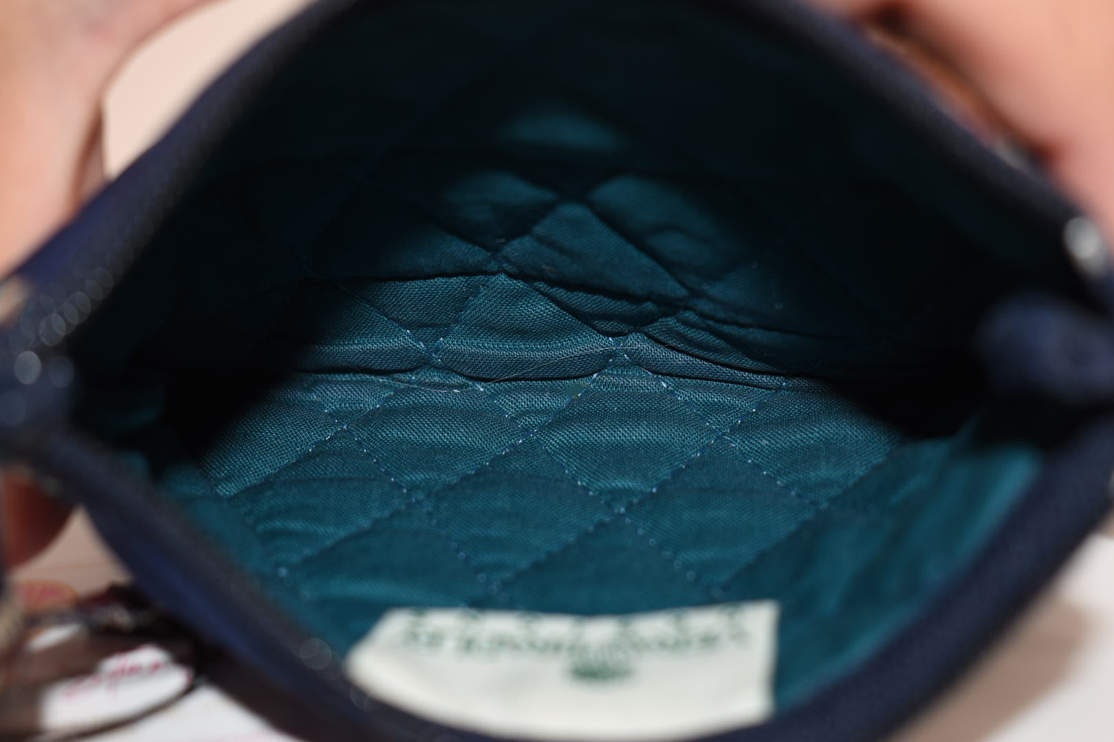 Close-up of a blue quilted pouch with a brand label.